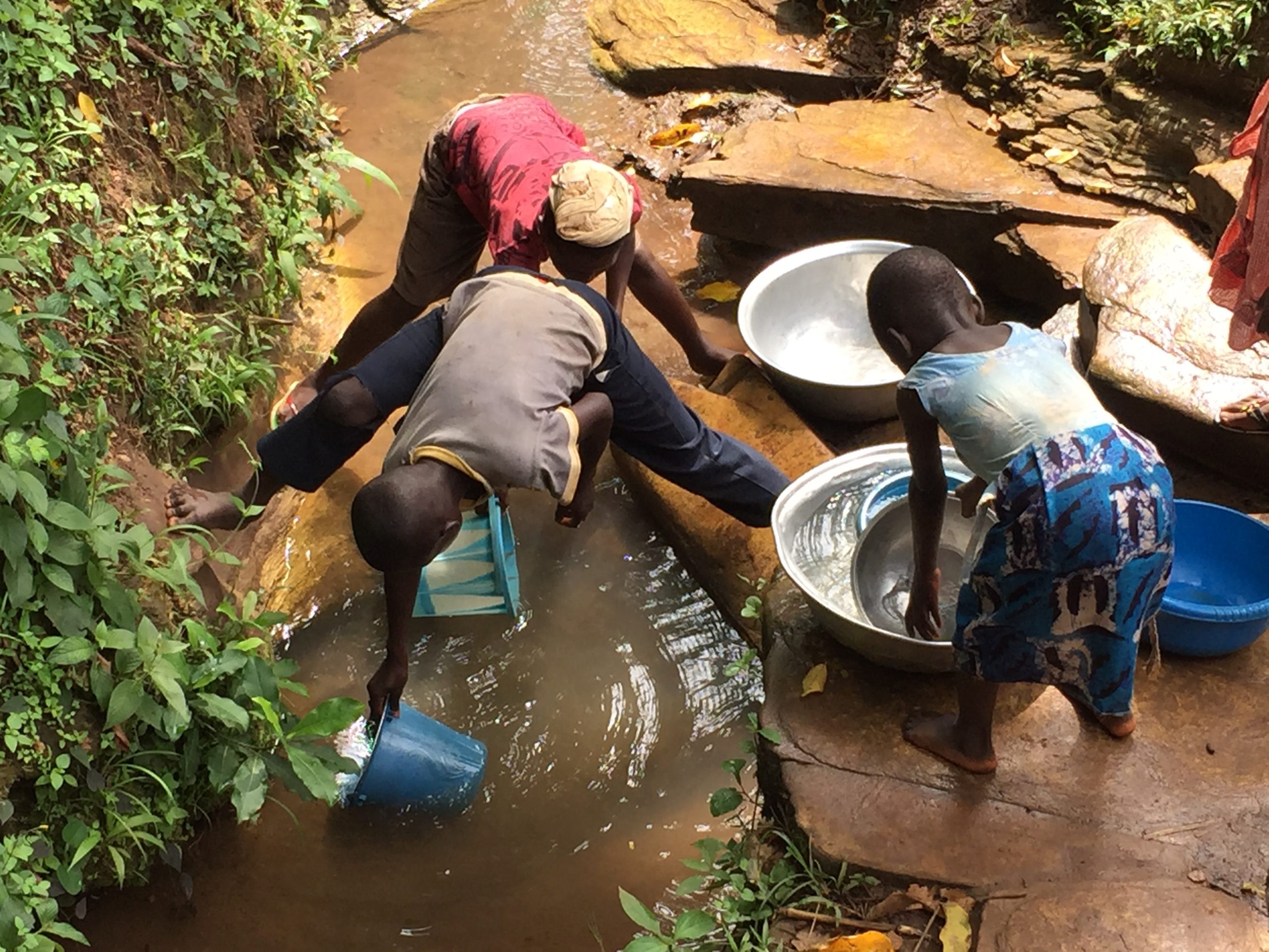 Famille togolaise prenant de l'eau dans un ruisseau