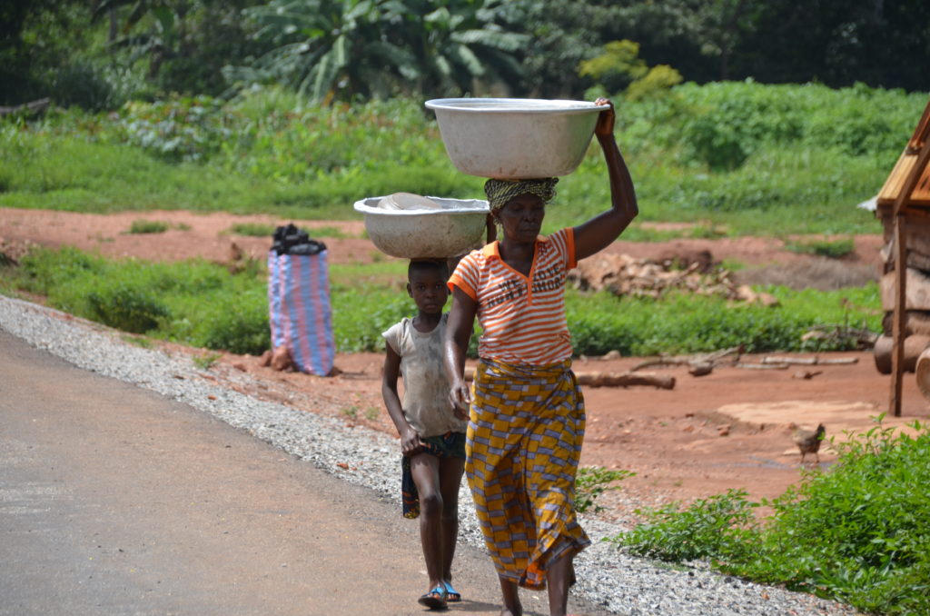 Femme et enfants rapportant l'eau grâce à des bassines sur leurs têtes